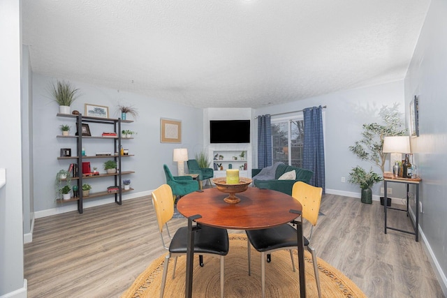 dining area with a textured ceiling and light hardwood / wood-style flooring