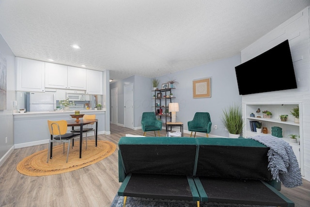 living room with built in features, light wood-type flooring, and a textured ceiling