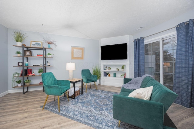 living room with hardwood / wood-style floors, a textured ceiling, and built in features