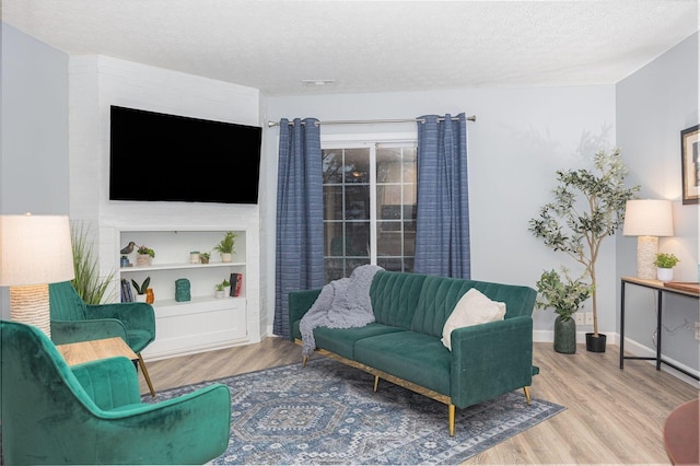 living room with built in shelves, light hardwood / wood-style floors, and a textured ceiling