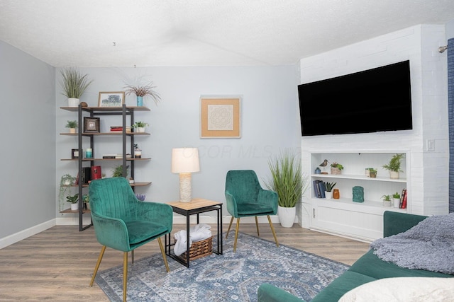 living area with wood-type flooring, a textured ceiling, and built in features