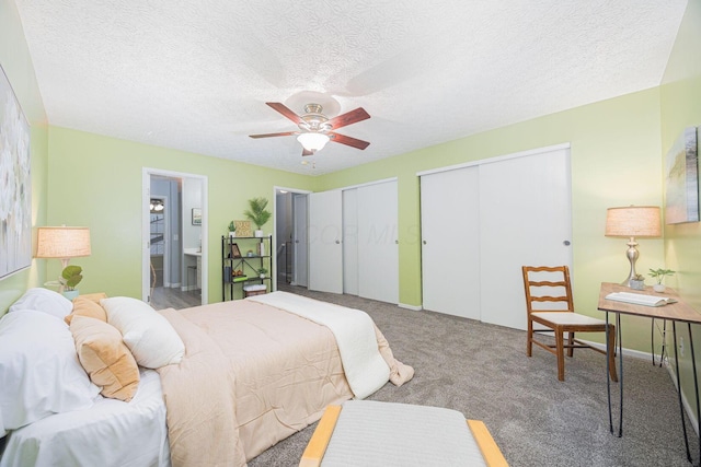 carpeted bedroom featuring ensuite bath, ceiling fan, multiple closets, and a textured ceiling