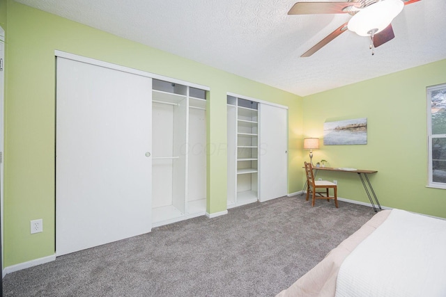 carpeted bedroom featuring ceiling fan, a textured ceiling, and two closets