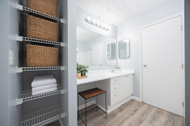 bathroom with hardwood / wood-style floors, vanity, and a textured ceiling