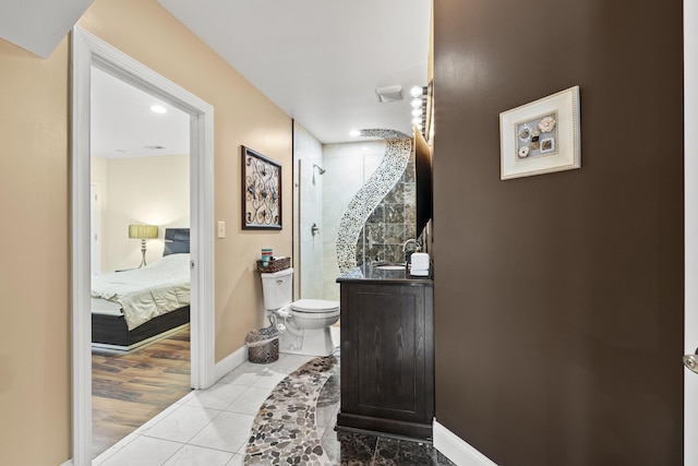 bathroom featuring tile patterned flooring, toilet, a tile shower, and vanity