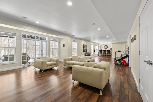 living room featuring dark hardwood / wood-style floors, crown molding, and a healthy amount of sunlight