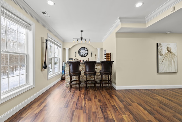 bar with dark hardwood / wood-style flooring, ornate columns, and crown molding