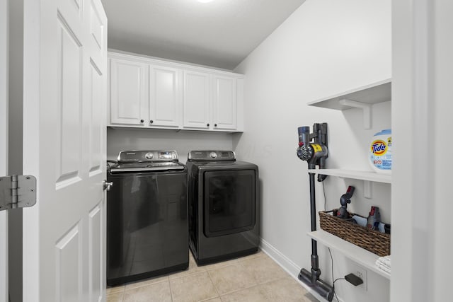 laundry room featuring cabinets, light tile patterned floors, and washing machine and clothes dryer