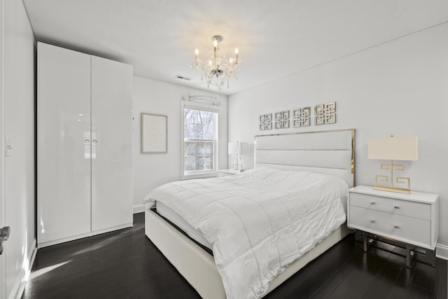 bedroom featuring a textured ceiling, dark wood-type flooring, and a notable chandelier