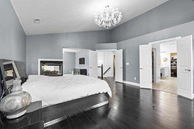 bedroom with a textured ceiling, an inviting chandelier, hardwood / wood-style flooring, and high vaulted ceiling