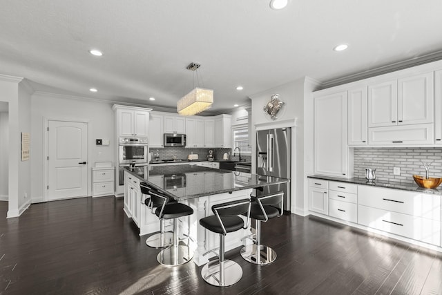 kitchen with a center island, stainless steel appliances, tasteful backsplash, pendant lighting, and white cabinets