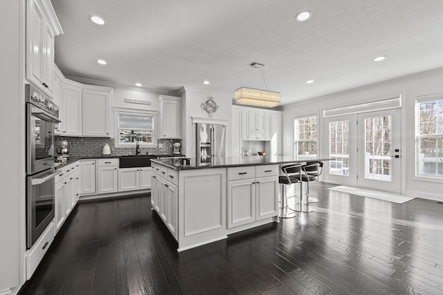 kitchen with backsplash, sink, hanging light fixtures, a kitchen island, and white cabinetry