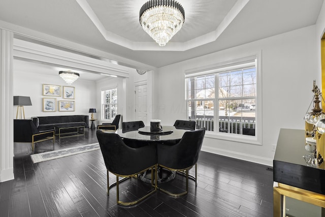 dining room with a raised ceiling, dark wood-type flooring, and a chandelier