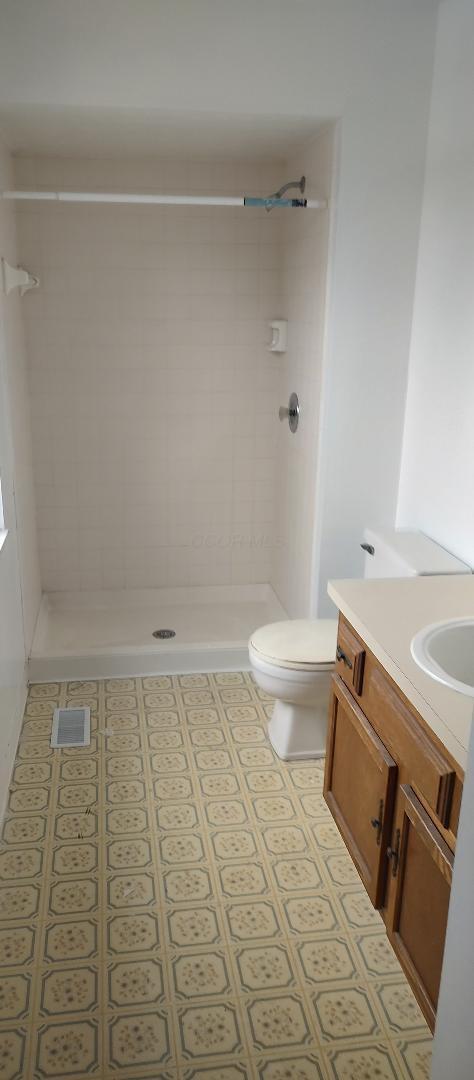 bathroom featuring vanity, toilet, and tiled shower