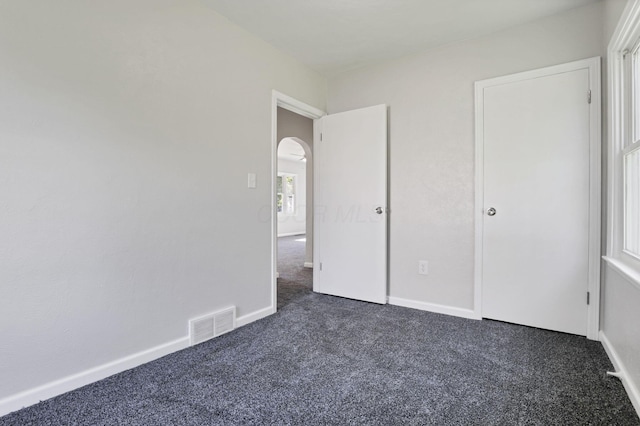 unfurnished bedroom with dark carpet