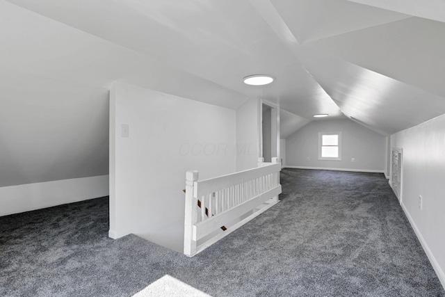 additional living space featuring dark colored carpet and vaulted ceiling