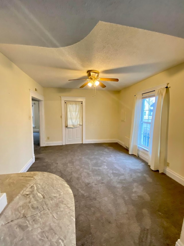 carpeted spare room featuring ceiling fan and a textured ceiling