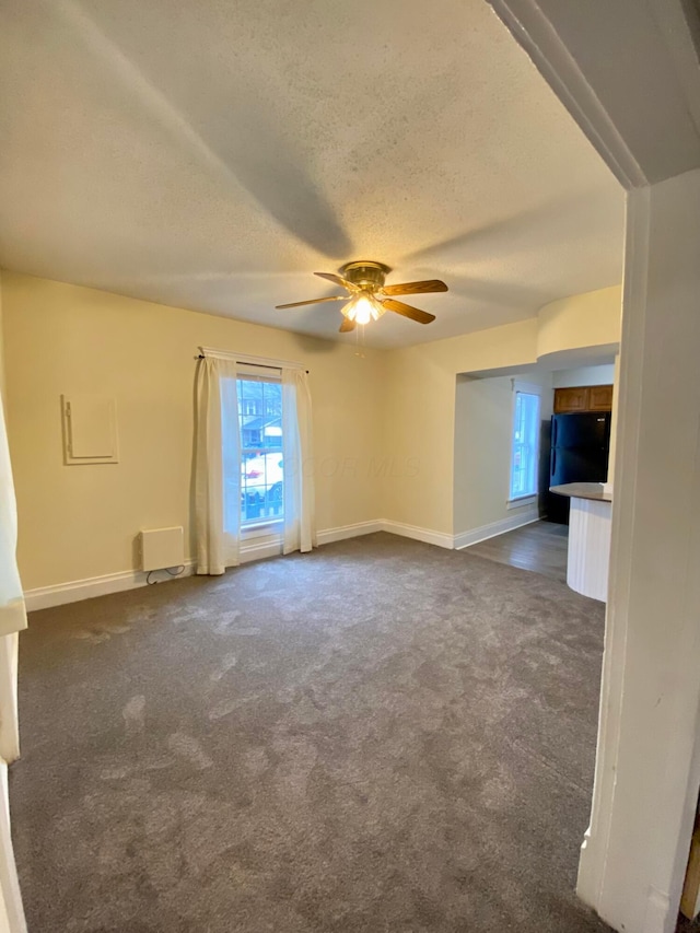 carpeted empty room with ceiling fan and a textured ceiling