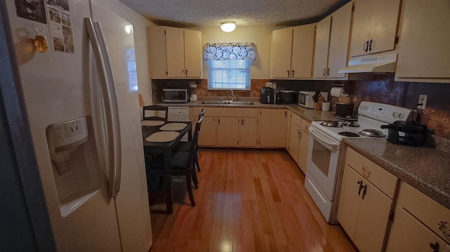 kitchen with white appliances, cream cabinets, sink, light wood-type flooring, and a textured ceiling