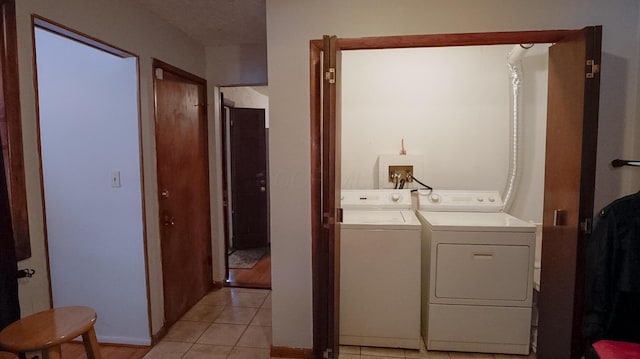 clothes washing area featuring light tile patterned flooring and washing machine and clothes dryer