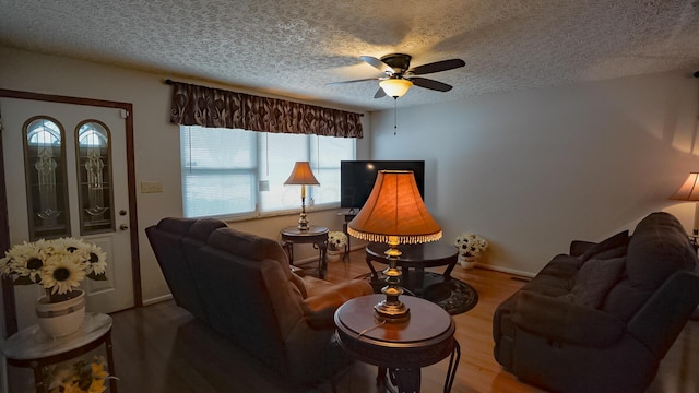 living room with ceiling fan, a textured ceiling, and hardwood / wood-style flooring