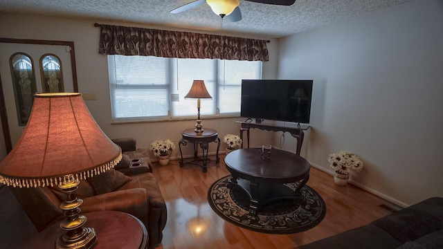 living room featuring ceiling fan, wood-type flooring, and a textured ceiling