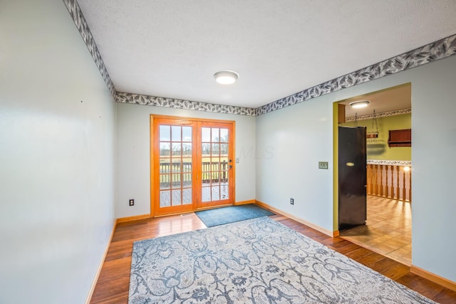 empty room featuring hardwood / wood-style flooring, a textured ceiling, and french doors