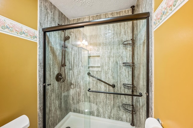 bathroom with a textured ceiling, toilet, and an enclosed shower