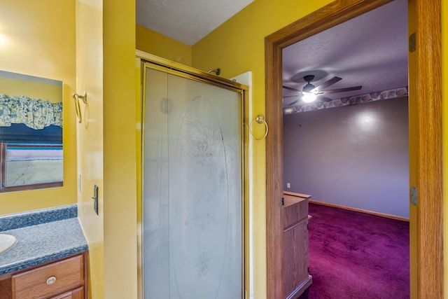 bathroom with ceiling fan, a shower with door, vanity, and a textured ceiling