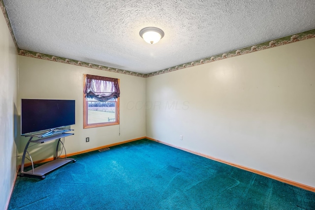 carpeted empty room with a textured ceiling