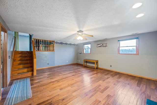 spare room with ceiling fan, a healthy amount of sunlight, a textured ceiling, and wood-type flooring