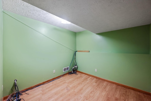 additional living space featuring hardwood / wood-style floors and a textured ceiling