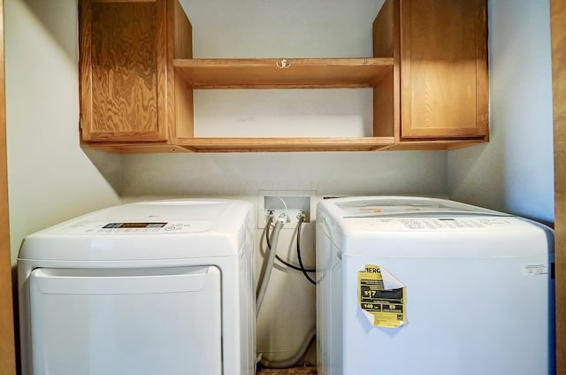 clothes washing area featuring cabinets and washer and dryer