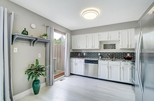 kitchen with decorative backsplash, light stone countertops, stainless steel appliances, sink, and white cabinets