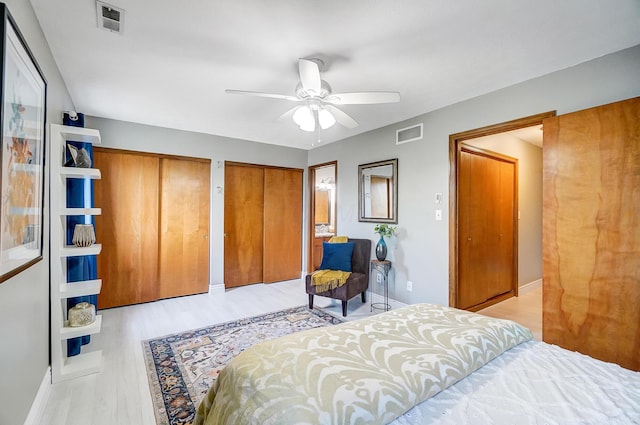 bedroom featuring ceiling fan, two closets, and light wood-type flooring