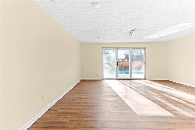 empty room with hardwood / wood-style floors and a textured ceiling