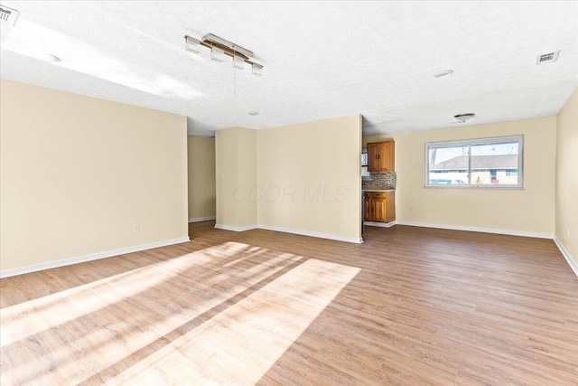 unfurnished living room featuring light hardwood / wood-style floors and a textured ceiling