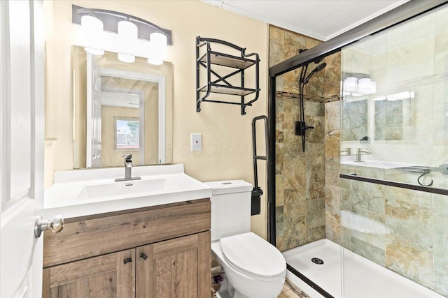 bathroom featuring vanity, toilet, a shower with shower door, and crown molding