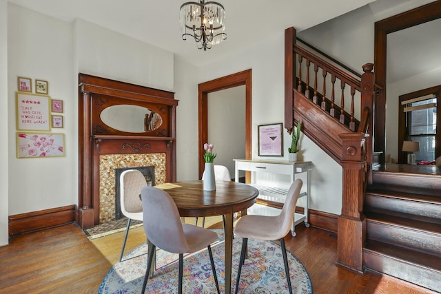 dining room featuring a tiled fireplace, a chandelier, and dark hardwood / wood-style floors