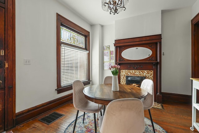 dining space featuring a tiled fireplace, dark wood-type flooring, and a notable chandelier