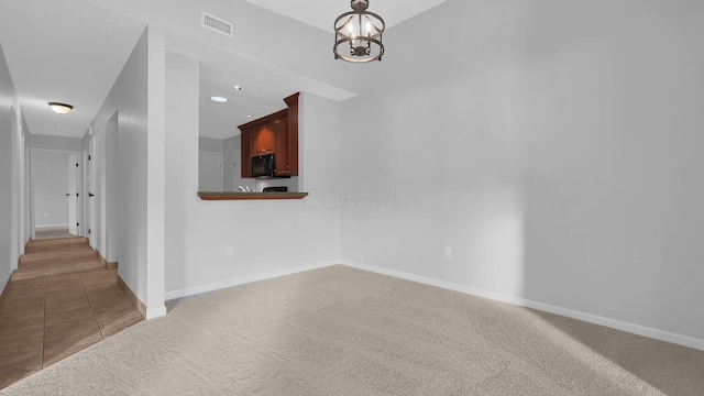 carpeted spare room with a notable chandelier