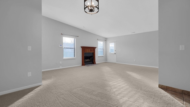 unfurnished living room featuring an inviting chandelier, lofted ceiling, and carpet flooring