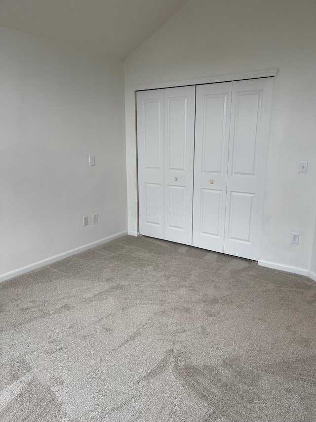 unfurnished bedroom with carpet, vaulted ceiling, and a closet