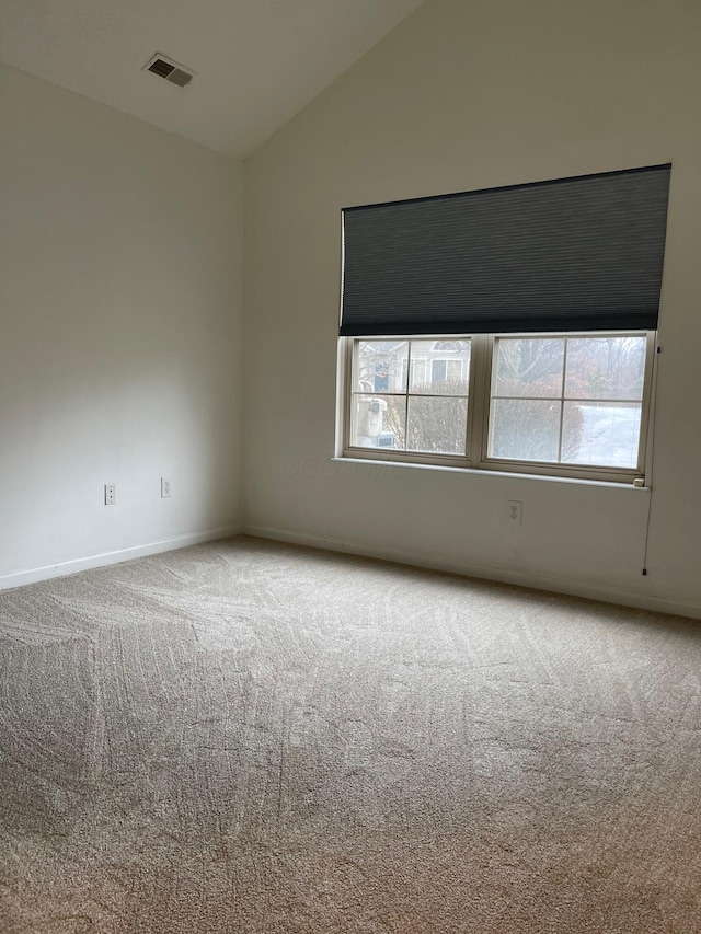 empty room featuring carpet flooring and vaulted ceiling