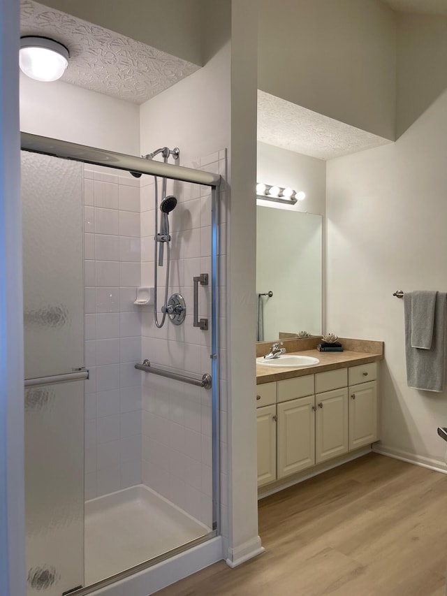 bathroom with hardwood / wood-style floors, vanity, a textured ceiling, and walk in shower