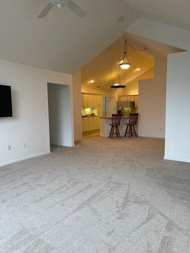 unfurnished living room with light carpet, ceiling fan, and vaulted ceiling