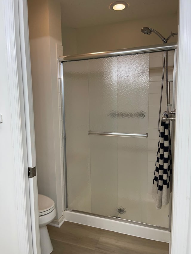 bathroom with wood-type flooring, an enclosed shower, and toilet