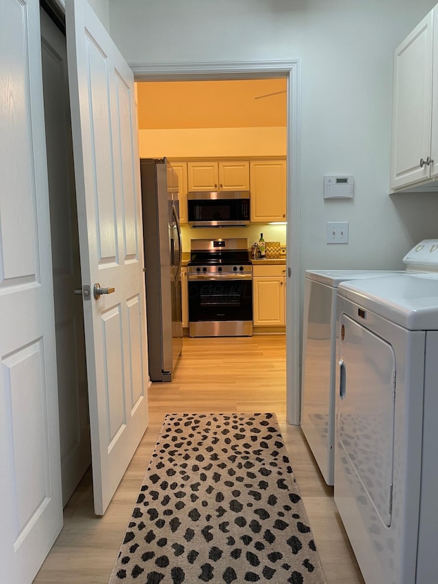 clothes washing area with washer and dryer and light hardwood / wood-style floors