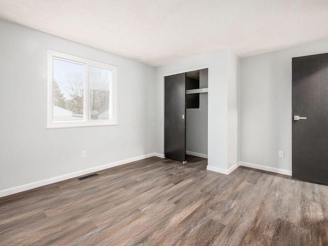 unfurnished bedroom with dark hardwood / wood-style floors and a closet