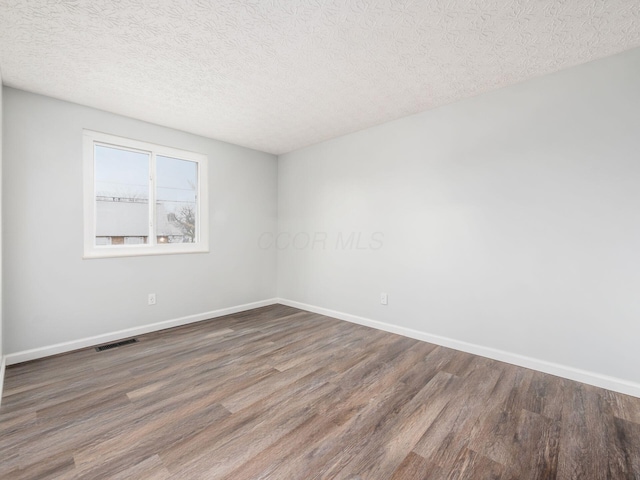 empty room featuring dark hardwood / wood-style floors and a textured ceiling